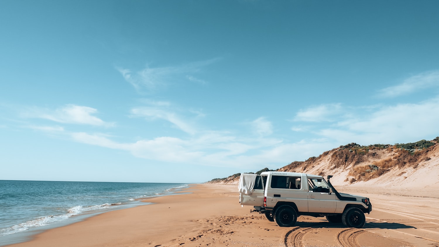 A Land Cruiser troop carrier parked on a wide Western Australian beach
